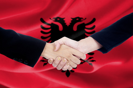 Two businesspeople shaking hands with albanian flag backgroundの写真素材