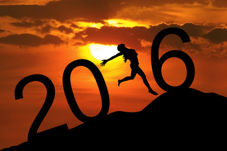 Silhouette young woman jumping on the hill and forming numbers 2016 while celebrating new year