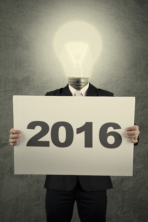 Image of businessman with lightbulb head holding poster with numbers 2016の写真素材