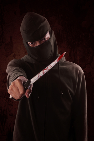 Terrorism concept: Terorrist holding a with blood in his hand.の写真素材