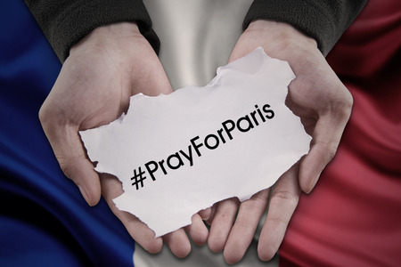 Hands with a piece of paper with #prayforparis printed on it.の写真素材