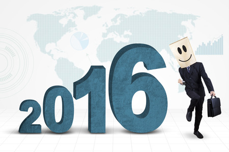 Happy businessman with cardboard head, celebrating his success with numbers 2016 and world mapの写真素材