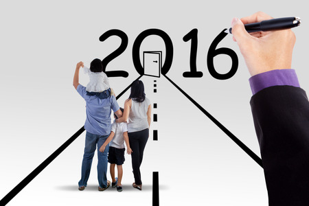 Image of happy family standing on the road and looking at a door with numbers 2016, isolated on...