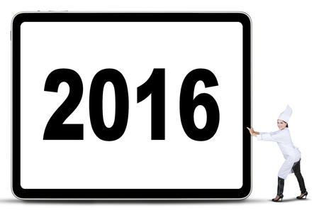 Portrait of female chef pushing a placard with number of 2016, isolated on white background