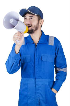 Middle eastern mechanic using a megaphone to announce information while wearing uniform in the studioの写真素材