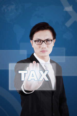 Young chinese businessman touching a tax button on the modern futuristic screenの写真素材