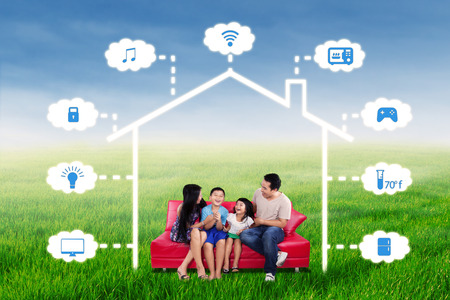 Portrait of joyful family having fun together on the sofa under a design of smart home technology systemの写真素材