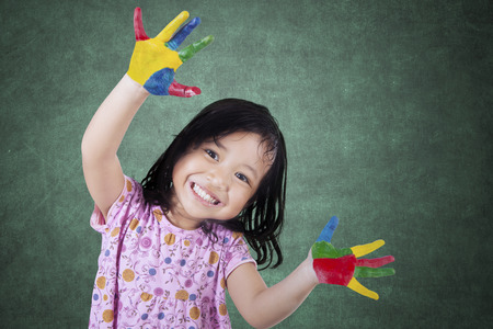 Portrait of a cute cheerful girl showing her hands painted in bright colorsの写真素材