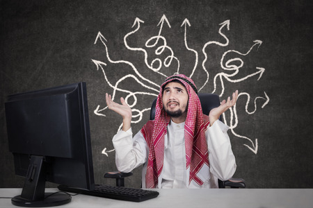 Picture of male Arabian entrepreneur wearing headscarf and looks confused to find solutionの写真素材