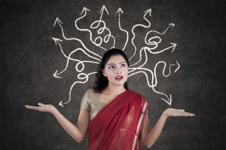 Portrait of Indian woman thinking a solution while wearing sari clothes with arrow on the blackboardの写真素材