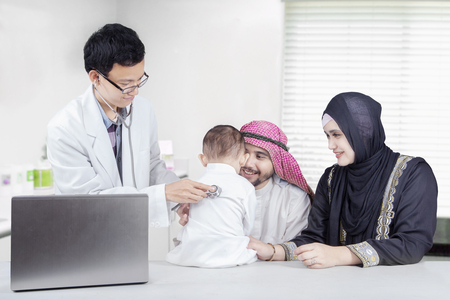 Picture of middle eastern family and their son visiting doctor in the hospitalの写真素材
