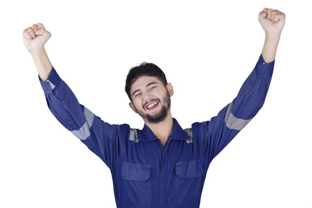 Male Arabic mechanic celebrating his success while raising hands in the studio, isolated on white backgroundの写真素材