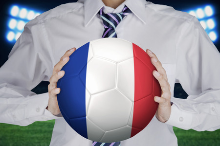 Close up of businessman holding a soccer ball with a France flag at field.の写真素材