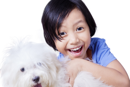 Portrait of a cute little girl holding her puppy and smiling at the camera, isolated on white backgroundの写真素材