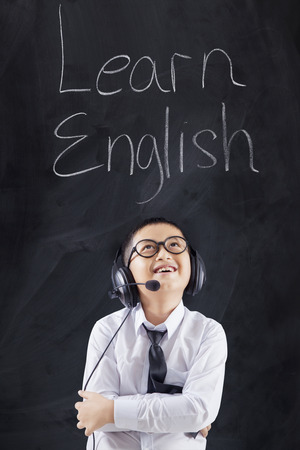 Male elementary school student learns English by listening with headphones in the classroomの写真素材