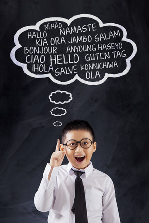 Photo of a cute schoolboy learns many language and say Hello in different languages, shot in the classの写真素材