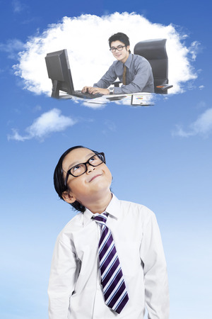 Cute little boy imagines work as a businessman while looking at speech bubbleの写真素材