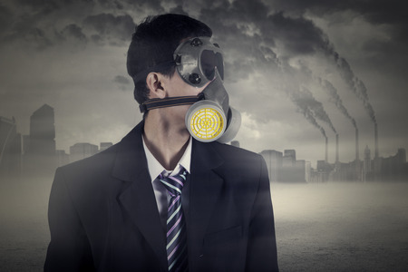 Image of male worker wearing a gas mask with air pollution background in the cityの写真素材