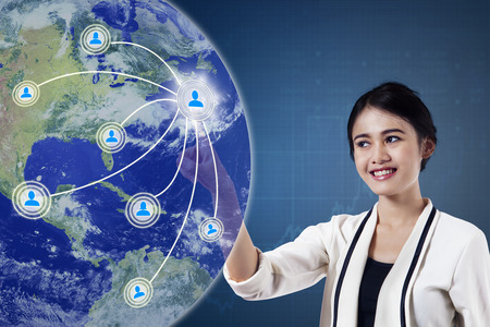 Concept of social media connection. Beautiful businesswoman pressing button on the virtual screen with social media icon and globeの写真素材