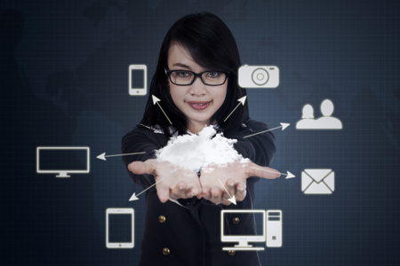 Image of a young businesswoman holding cloud computing icons: cloud, tablet, smartphone, computer, digital cameraの写真素材