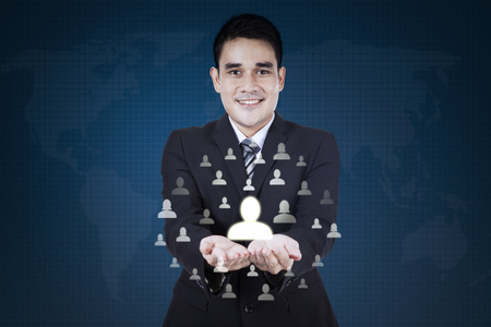 Young businessman smiling at the camera while showing social network icon on his handの写真素材