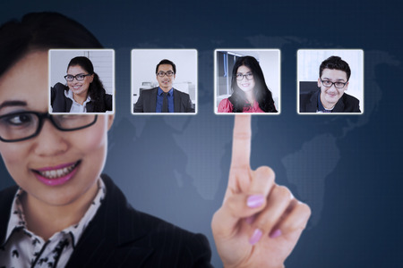 Young businesswoman pressing virtual screen and choosing her partner profile on social networkの写真素材