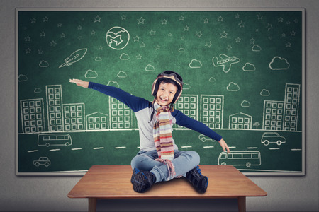 Portrait of little child flying on the table with doodle background at chalkboardの写真素材