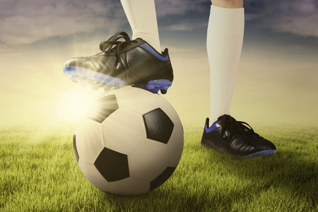 Close up of foot of football player and a ball ready to start a game on the meadowの写真素材