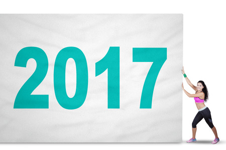 Concept of Happy New Year 2017. Picture of a fit woman wearing sportswear and pulling a big flag...
