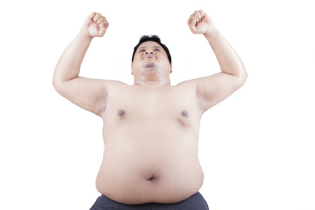 Portrait of fat man raising his hands and doing exercise in the studio, isolated on white backgroundの写真素材
