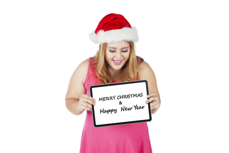 Cheerful woman is showing a greeting board with text of Merry Christmas and Happy New Year, isolated on white backgroundの写真素材