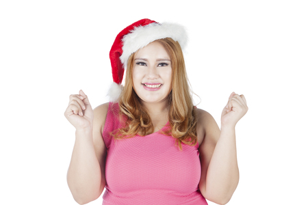 Portrait of cheerful fat woman wearing santa hat and smiling at camera, isolated on white backgroundの写真素材
