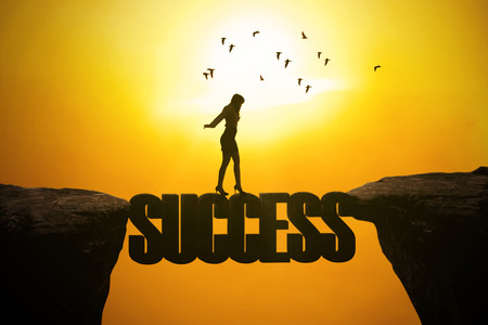 Silhouette of businesswoman walking through a bridge on the mountain with success wordの写真素材