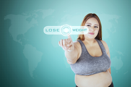 Portrait of woman touching start button with lose weight on the virtual screenの写真素材