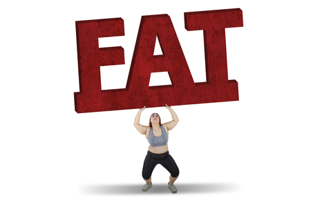 Picture of overweight woman lifting a big fat word while standing in studio, isolated on white backgroundの写真素材