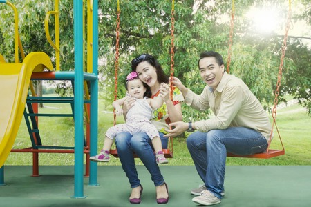Portrait of cheerful family playing together in playground while smiling at the cameraの写真素材