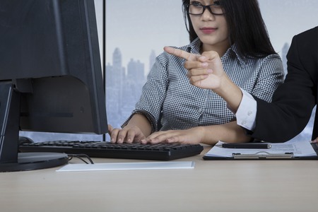 Hand of a male leader pointing and discussing a task on the computer to his assistant, with winter background on the windowの写真素材