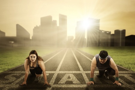 Portrait of overweight people kneel on the start line while ready to compete and try to chase their dreamの写真素材