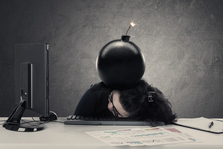 Frustrated entrepreneur sleeping on the desk with bomb over her head, concept of financial bankruptの写真素材