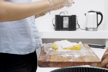 Close up of wife pouring flour for pie dough on the wooden board in the kitchenの写真素材