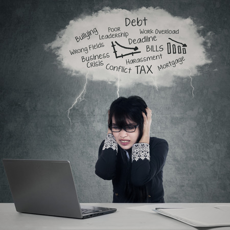 Picture of a stressful businesswoman having headache while working under cloud of his problemsの写真素材