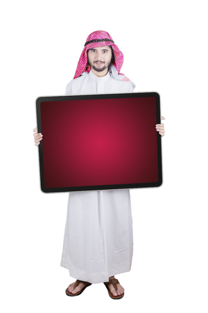 Arabian businessman wearing traditional clothes while holding empty board on the studioの写真素材