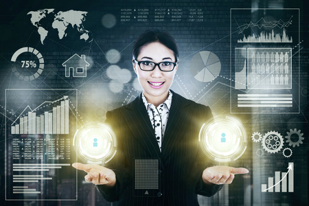 Portrait of young female entrepreneur showing two button icon while standing with virtual growth businessの写真素材