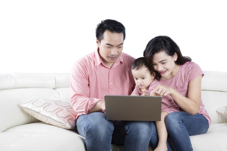 Image of happy family using a laptop for watching a movie while sitting on the couch, isolated on white backgroundの写真素材