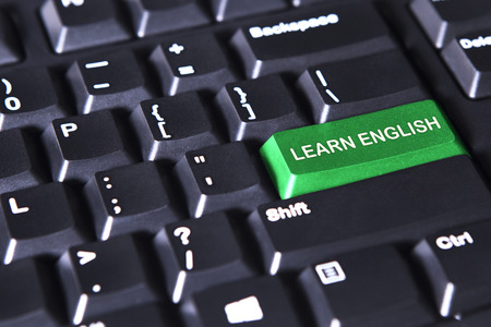 Image of computer keyboard with text of learn English on the green buttonの写真素材