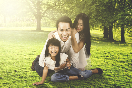 Portrait of joyful family enjoying leisure time while relaxing and laughing together at the parkの写真素材