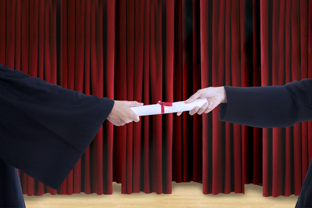 Close-up of hands giving certificate on stage during graduationの写真素材