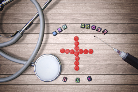 World Red Cross Day concept. A red cross symbol made of medication with a stethoscope and syringe on the wooden tableの写真素材