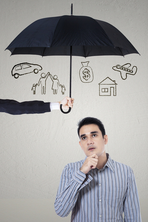Picture of a pensive young man imagining her wish under umbrella. dreams insured conceptの写真素材