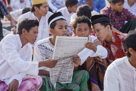 JAKARTA, Indonesia. April 18, 2017: four men Muslim reads a newspaper while sitting in the field...